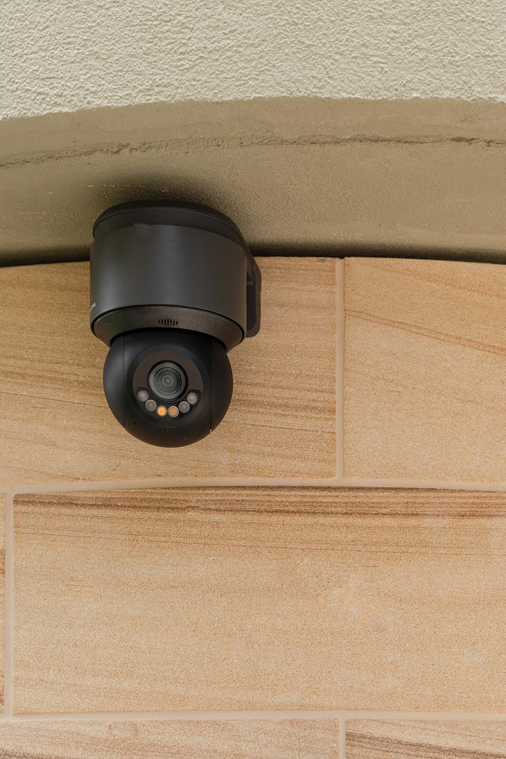Close-up of a black security camera mounted on an exterior wall