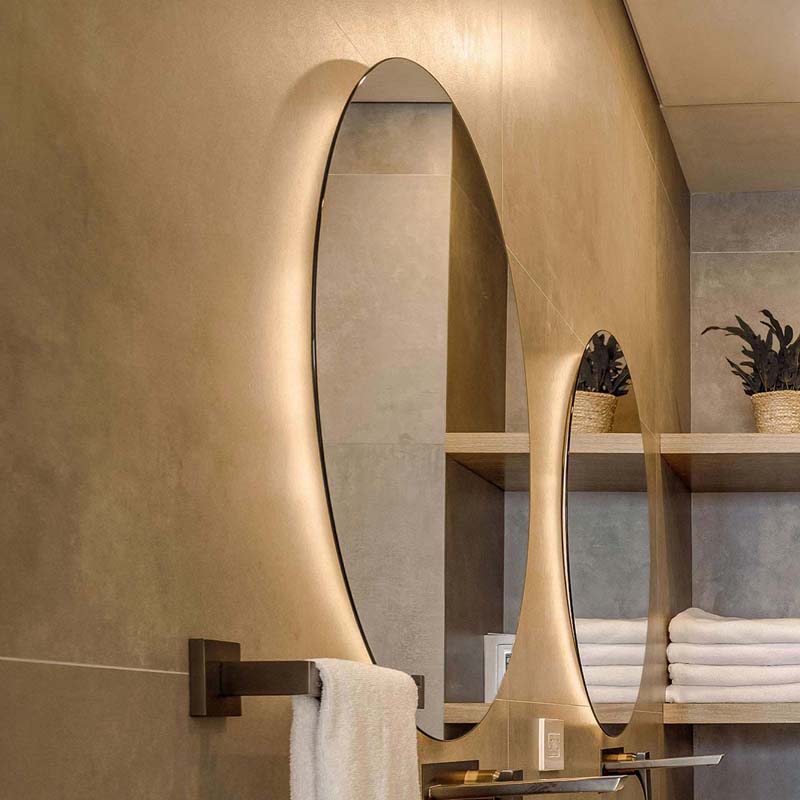 Circular mirror with embedded LED backlighting, installed above a minimalist sink for consistent, shadow-free illumination.