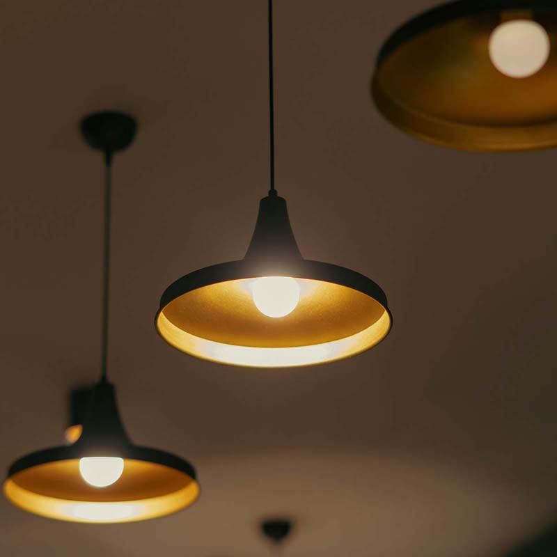 Close-up of black pendant lights with gold interiors, hanging in a minimalist space.