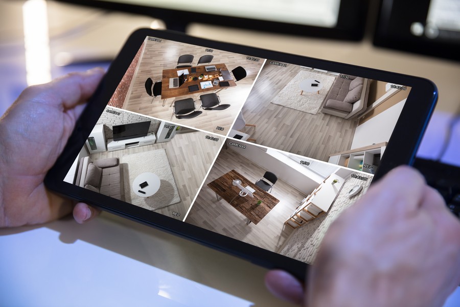 Closeup of a person monitoring his home surveillance cameras from a tablet. 