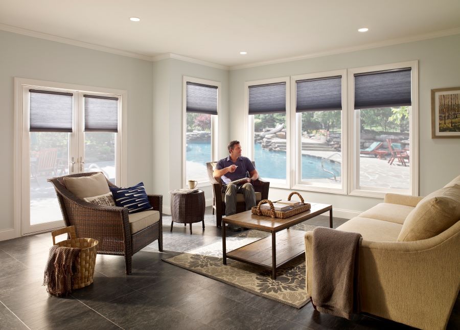 A man sitting in a sunroom. Lutron’s motorized shades are partially drawn on all the windows.