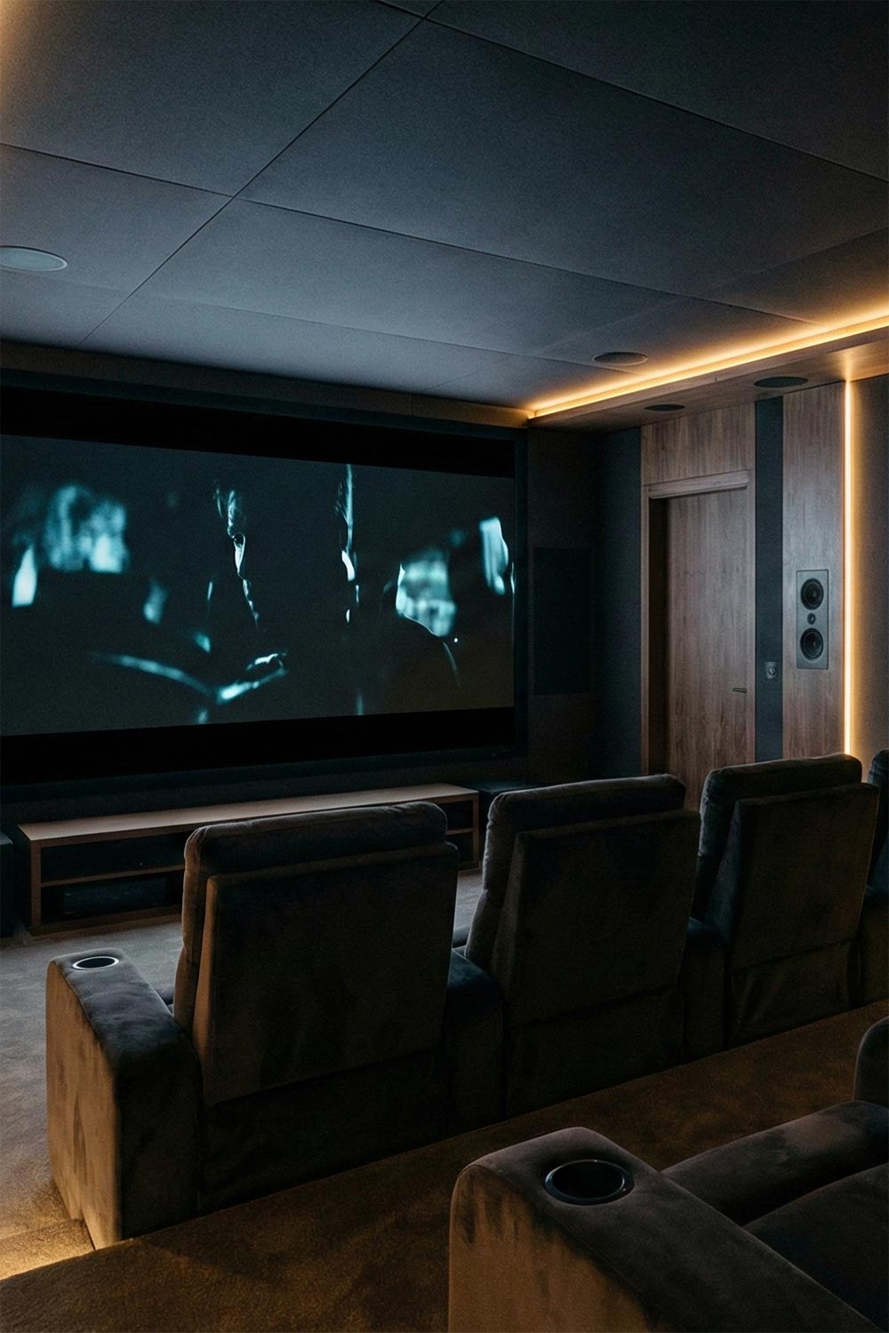 Modern dark theater room with wood panels and plush reclining seats