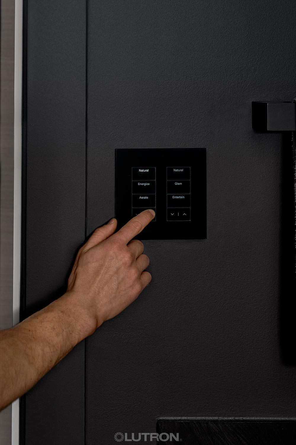 Hand selecting lighting mode on a sleek wall control panel