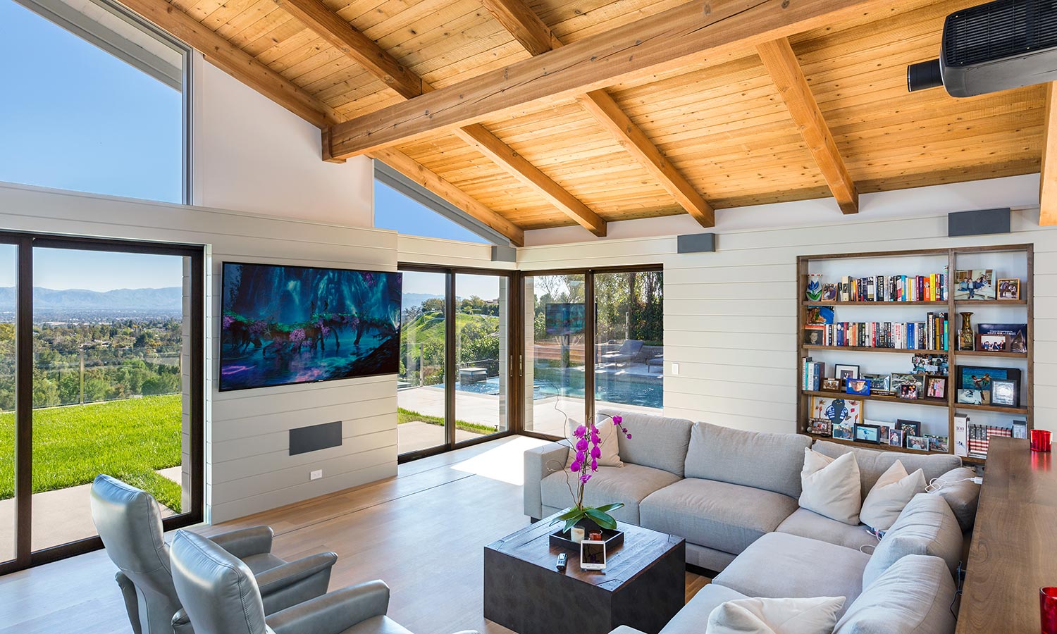 A luxurious living room featuring a large TV above a sleek fireplace, a marble coffee table, and a comfortable seating area, emphasizing a blend of modern and rustic elements.