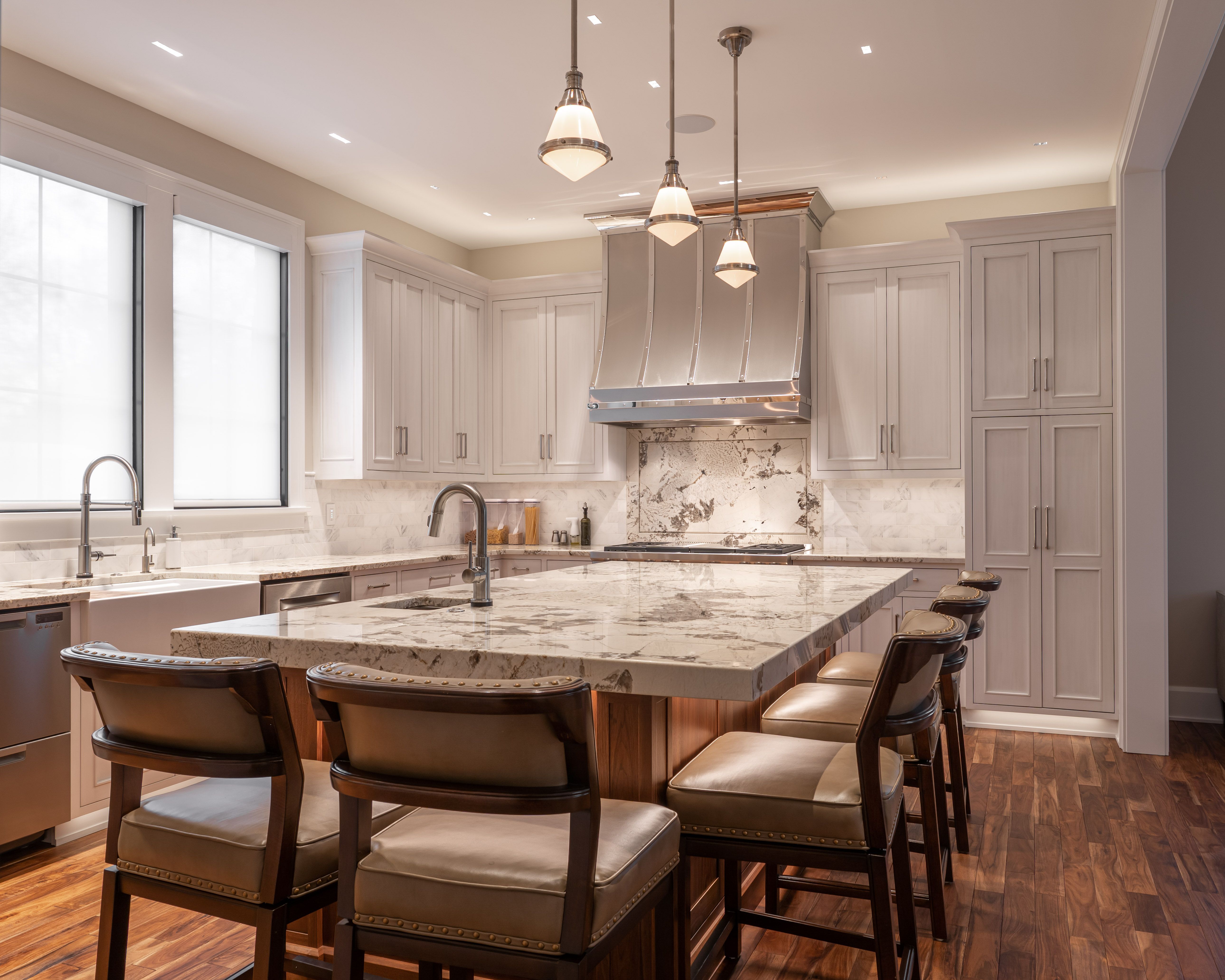 A brightly lit modern kitchen with a large marble island and elegant cabinetry.