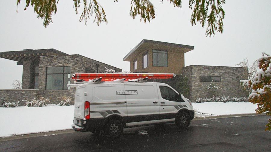 A work van parked outside a snow-covered modern home during winter.