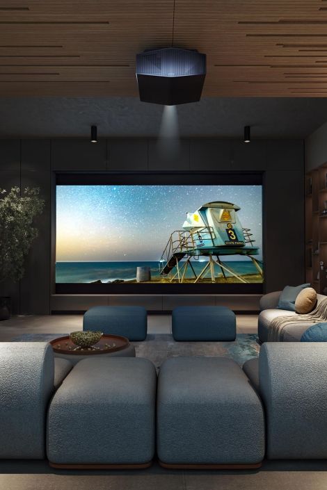 A cozy home theater with blue seating and a large projection screen displaying a scenic image.